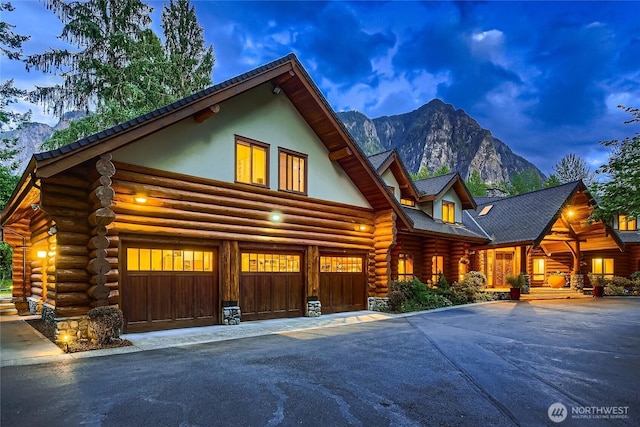 log cabin with a mountain view, a garage, log exterior, and driveway