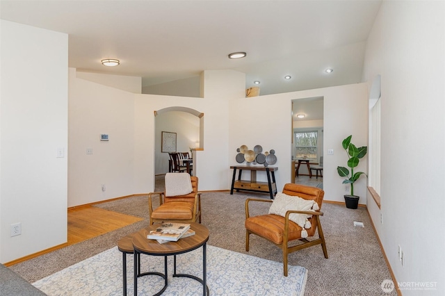 living area with baseboards, lofted ceiling, and arched walkways