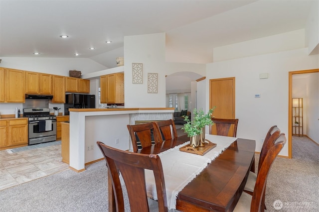 dining space with vaulted ceiling, recessed lighting, arched walkways, and light carpet