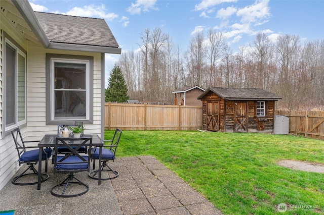 view of yard with a shed, an outdoor structure, a fenced backyard, a patio area, and outdoor dining space