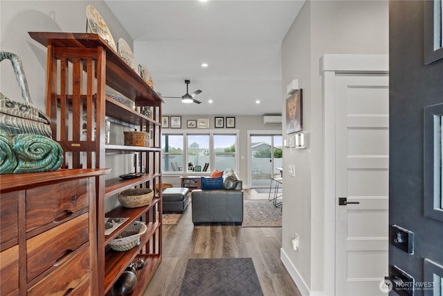 hall featuring recessed lighting, baseboards, an AC wall unit, and wood finished floors