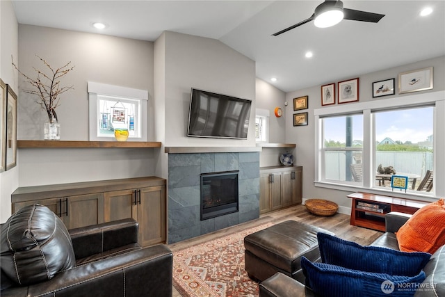 living area with a ceiling fan, wood finished floors, lofted ceiling, recessed lighting, and a fireplace