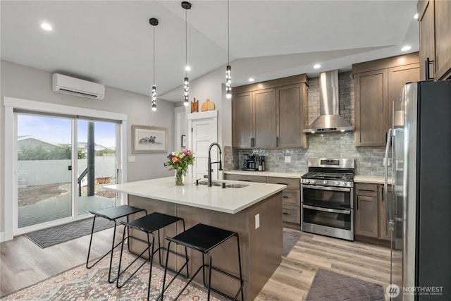 kitchen featuring an AC wall unit, a sink, tasteful backsplash, stainless steel appliances, and wall chimney exhaust hood