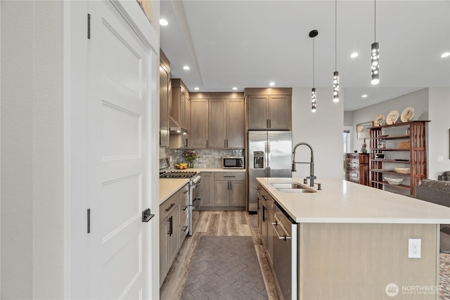 kitchen featuring recessed lighting, a sink, light countertops, appliances with stainless steel finishes, and backsplash