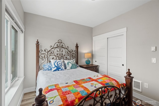 bedroom featuring visible vents, baseboards, a closet, and wood finished floors