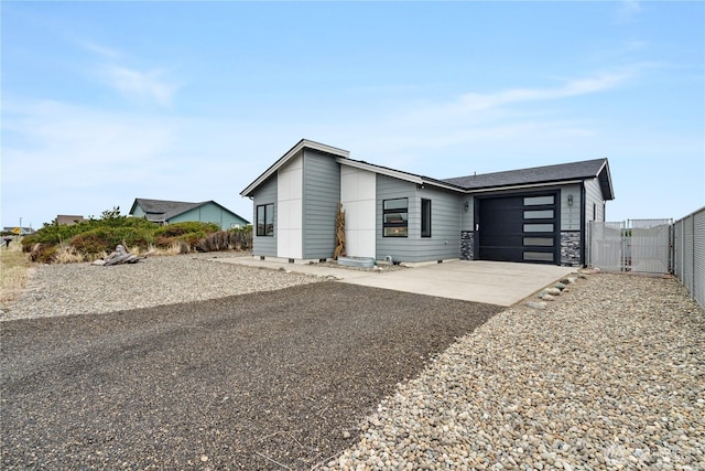 view of front facade with driveway, an attached garage, fence, and a gate