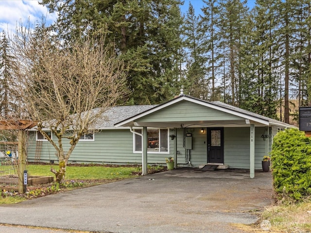 ranch-style home featuring a carport, driveway, and a shingled roof