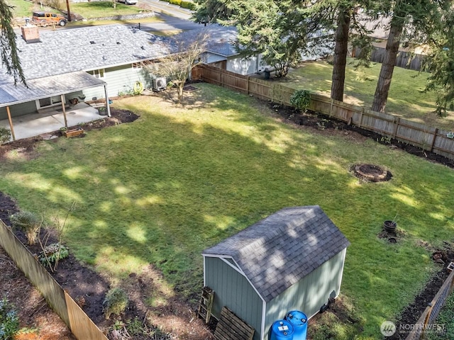 view of yard featuring a fenced backyard, a fire pit, a patio, and an outdoor structure