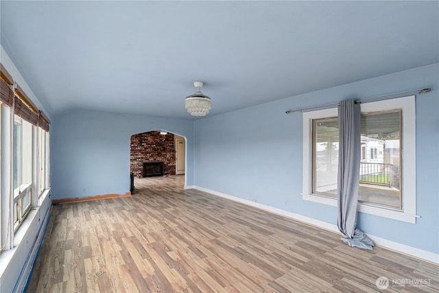 unfurnished living room with light wood-style flooring, a brick fireplace, baseboards, and a baseboard radiator