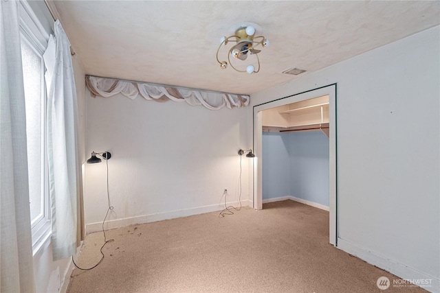 unfurnished bedroom with baseboards, multiple windows, carpet, and visible vents