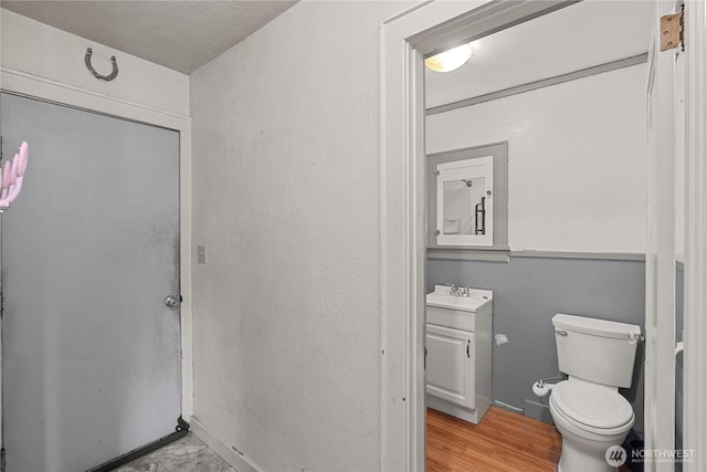 half bathroom featuring vanity, toilet, and wood finished floors