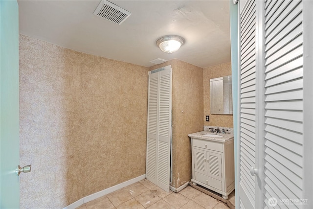 bathroom with vanity, baseboards, visible vents, tile patterned flooring, and a closet