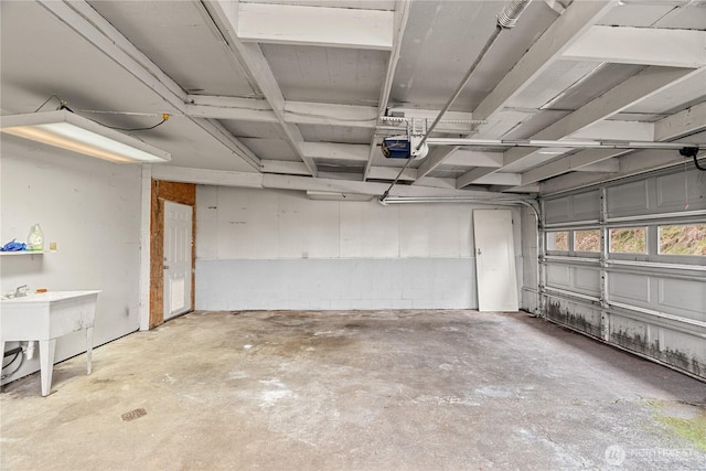 garage featuring concrete block wall, a garage door opener, and a sink