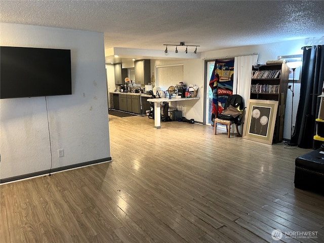 living area featuring a textured ceiling, baseboards, and wood finished floors