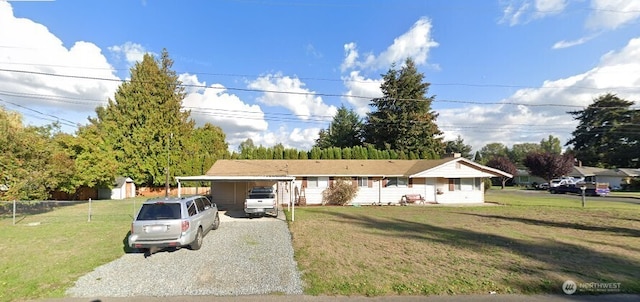 single story home with an attached carport, gravel driveway, a front yard, and fence