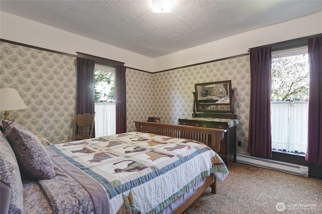 carpeted bedroom with a textured ceiling, wallpapered walls, and a baseboard heating unit