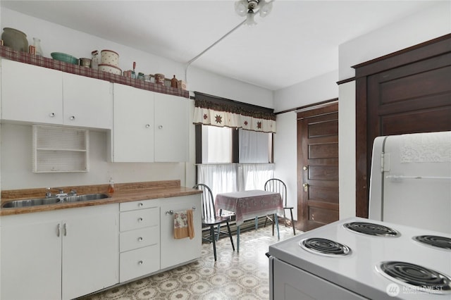 kitchen featuring white cabinetry, white appliances, light floors, and a sink