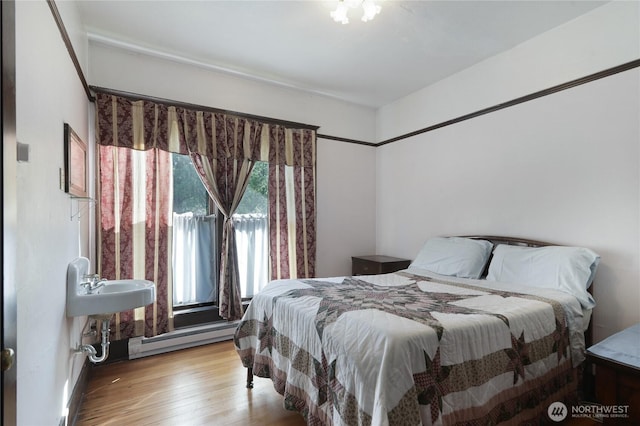 bedroom featuring a baseboard heating unit and wood finished floors