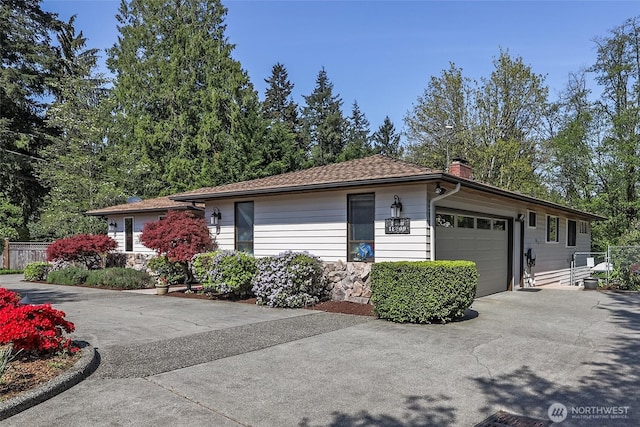 view of front of home featuring driveway, a garage, fence, and a chimney
