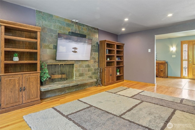 unfurnished living room featuring recessed lighting, a large fireplace, wood finished floors, and baseboards