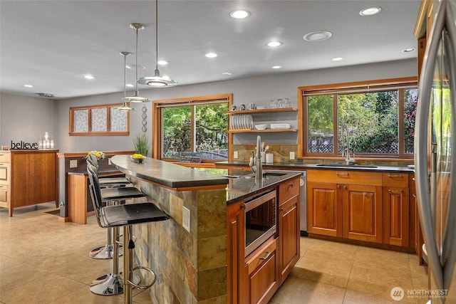 kitchen featuring recessed lighting, a breakfast bar area, stainless steel appliances, brown cabinets, and a sink