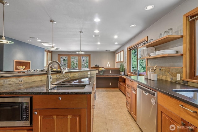 kitchen featuring a sink, stainless steel appliances, a healthy amount of sunlight, and brown cabinets