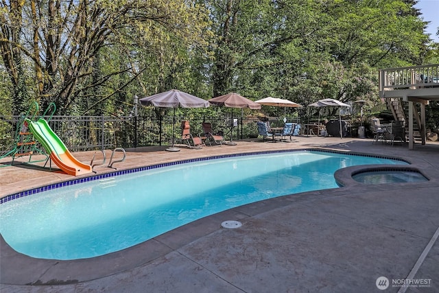 view of pool with a patio, stairs, a pool with connected hot tub, and fence