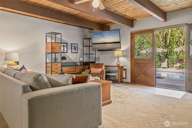 carpeted living room featuring beamed ceiling, a ceiling fan, wooden ceiling, and tile patterned floors