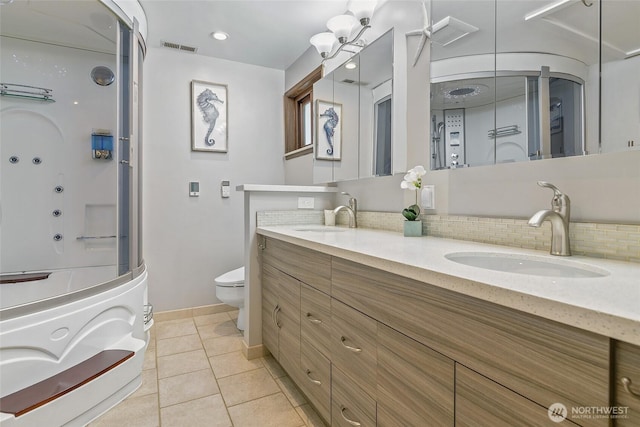 bathroom featuring tasteful backsplash, visible vents, toilet, and a sink