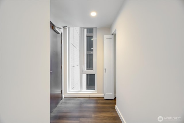 corridor featuring baseboards and wood finished floors