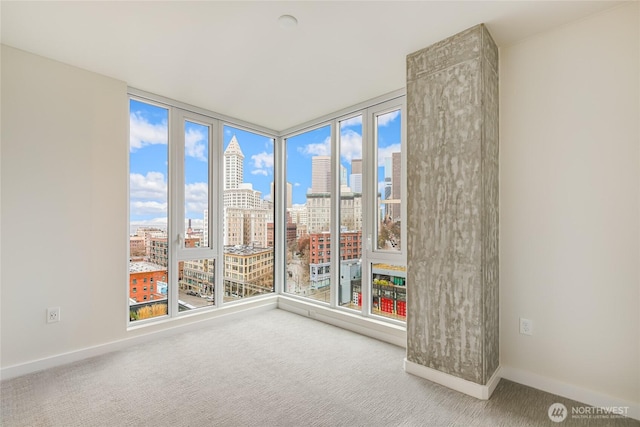 spare room featuring carpet flooring, a view of city, and baseboards