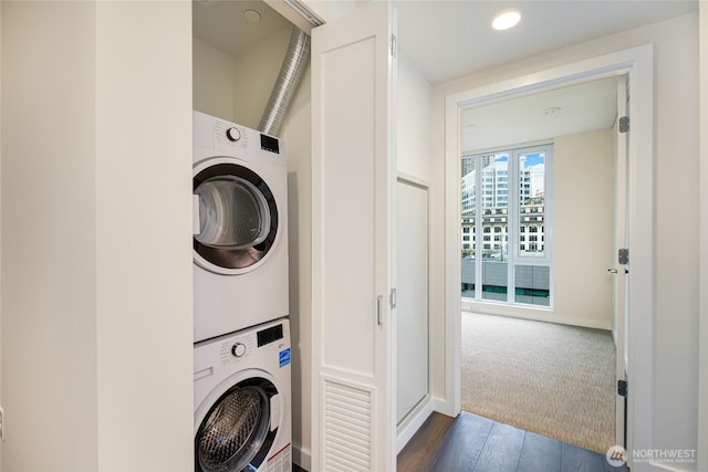 laundry room with stacked washer / drying machine, dark wood-style floors, and laundry area