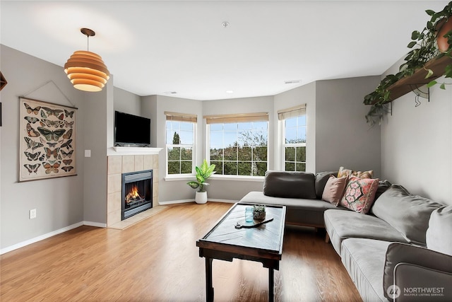 living area with visible vents, a fireplace, baseboards, and wood finished floors