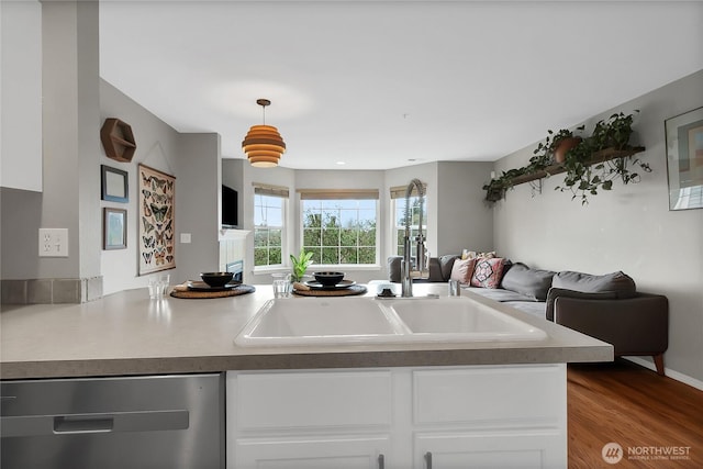 kitchen featuring wood finished floors, open floor plan, a peninsula, white cabinets, and dishwasher