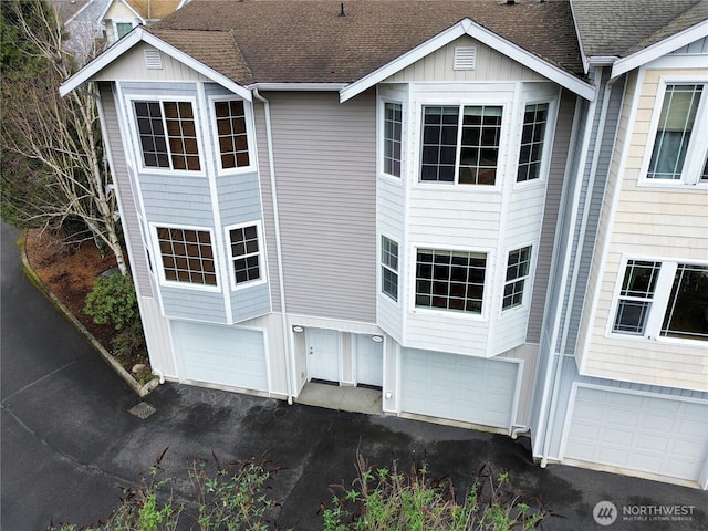 exterior space featuring a garage, driveway, and a shingled roof