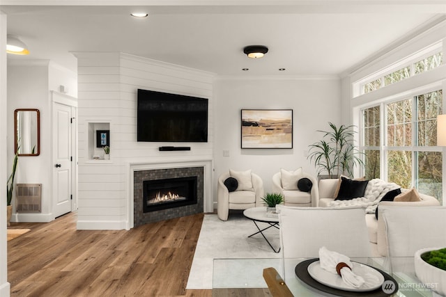 living room with visible vents, ornamental molding, recessed lighting, a fireplace, and wood finished floors