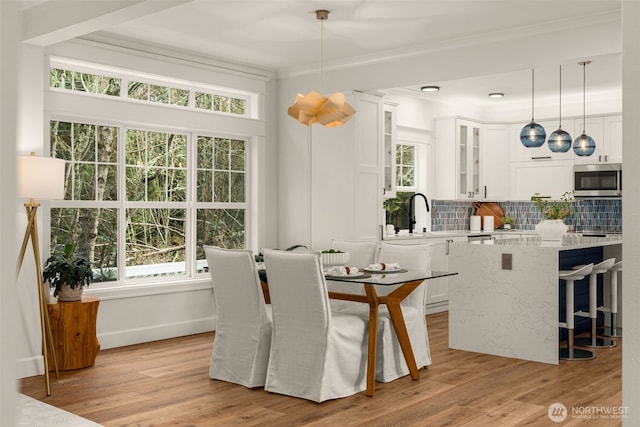 dining area with light wood-style flooring, a wealth of natural light, and ornamental molding