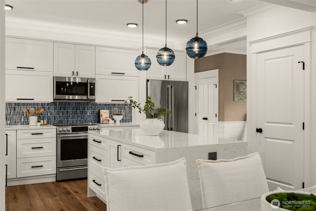 kitchen featuring ornamental molding, light stone counters, a center island, stainless steel appliances, and white cabinets