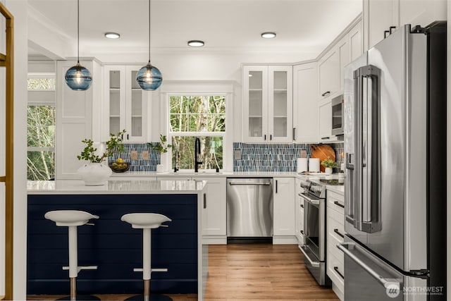 kitchen featuring a breakfast bar area, a sink, light countertops, appliances with stainless steel finishes, and tasteful backsplash