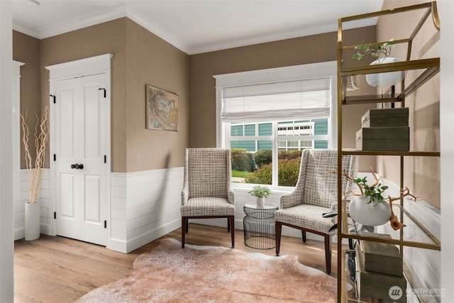 sitting room featuring wood finished floors, a wainscoted wall, and ornamental molding