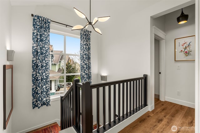 stairway with a chandelier, baseboards, wood finished floors, and vaulted ceiling