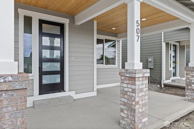 property entrance with a porch and brick siding