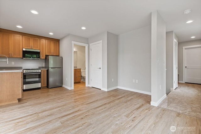 kitchen featuring recessed lighting, light wood-style floors, appliances with stainless steel finishes, and brown cabinetry