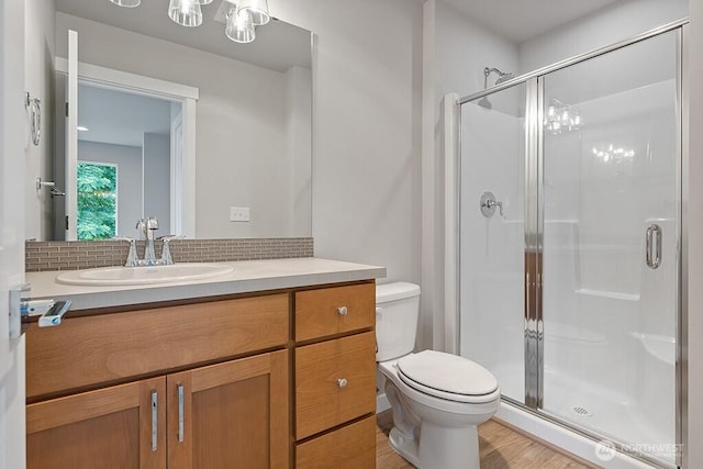 full bath with toilet, a stall shower, tasteful backsplash, wood finished floors, and vanity