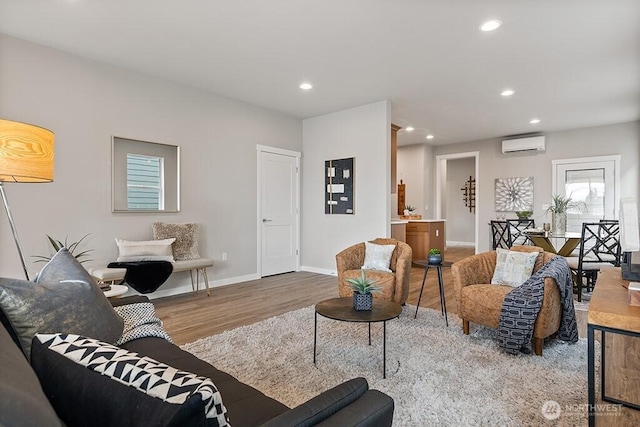 living area with recessed lighting, wood finished floors, baseboards, and a wall mounted air conditioner