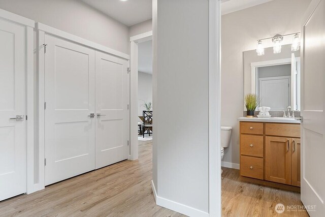 bathroom with vanity, toilet, wood finished floors, and baseboards