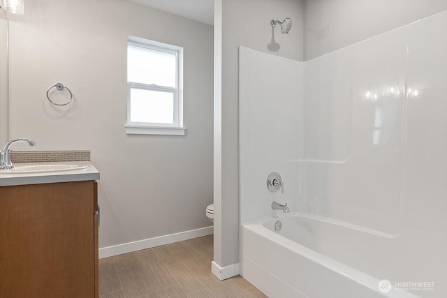 bathroom with shower / washtub combination, toilet, vanity, and baseboards