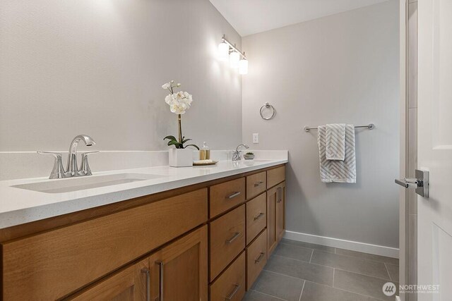 full bath featuring double vanity, tile patterned flooring, baseboards, and a sink