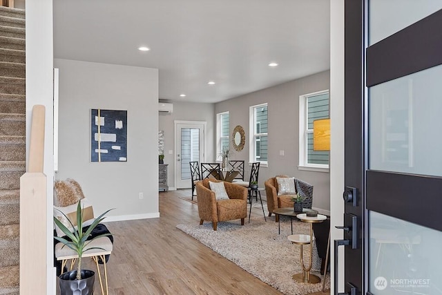 foyer with wood finished floors, a wall unit AC, recessed lighting, stairway, and baseboards