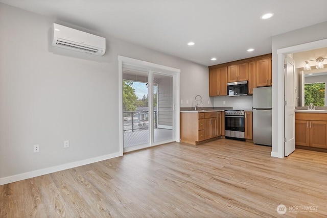 kitchen with a sink, an AC wall unit, plenty of natural light, and appliances with stainless steel finishes